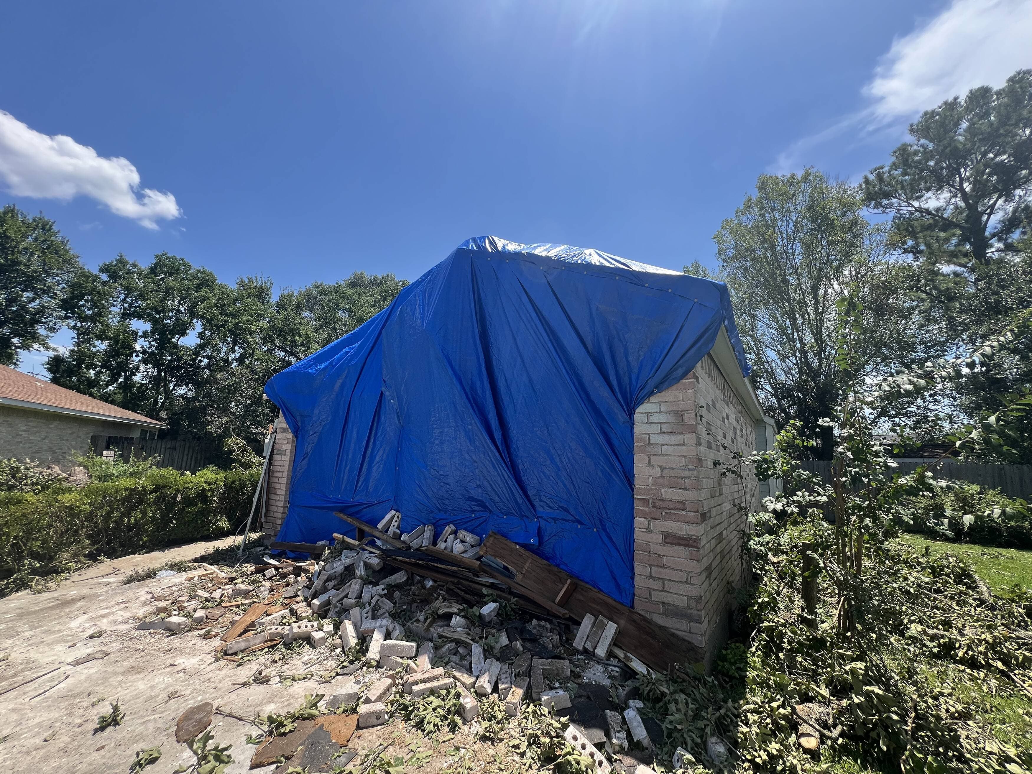Emergency tarp secured over a storm-damaged garage