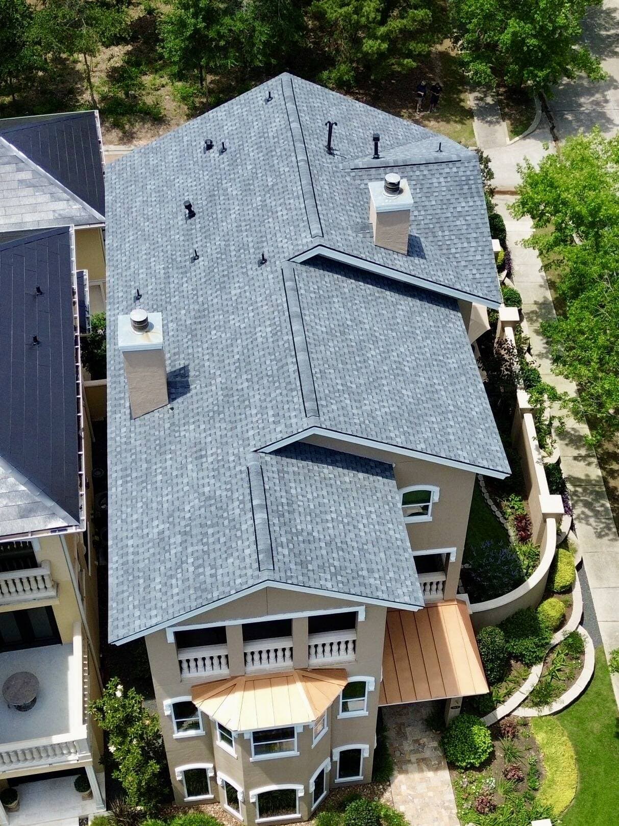 Drone view of a newly completed shingle roof with copper accent detailing